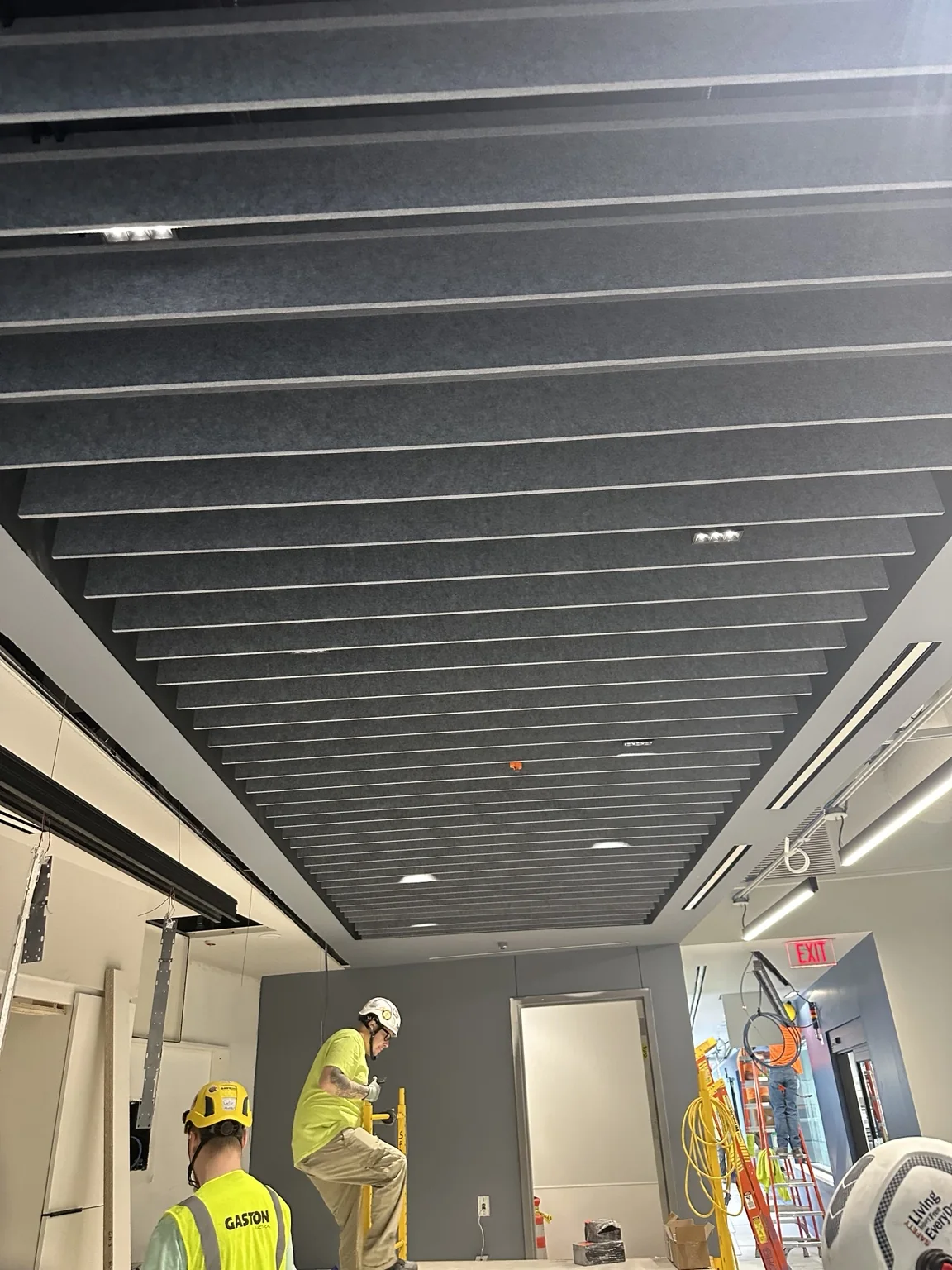 Dark suspended acoustic baffle ceiling during final installation