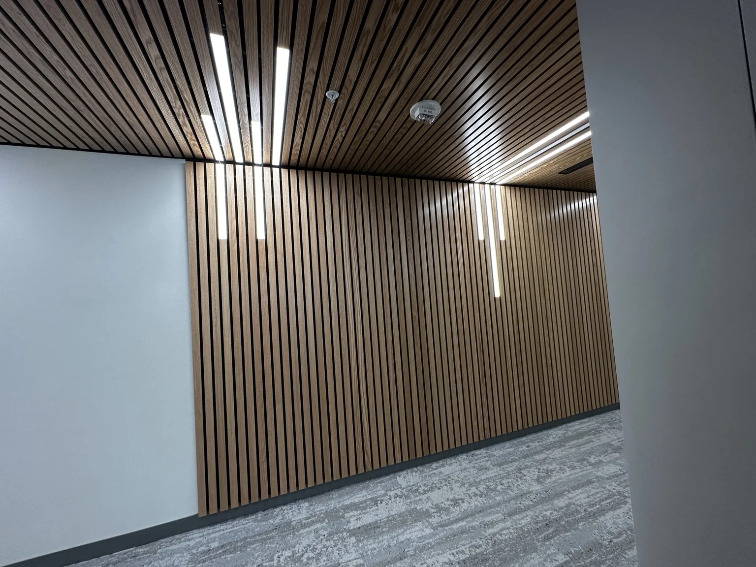 Finished architectural wood slat ceiling and wall with integrated linear lighting