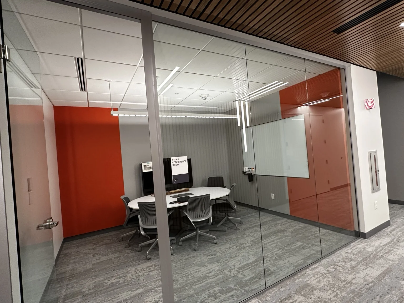 Finished glass conference room with suspended ceiling, lighting, and accent walls