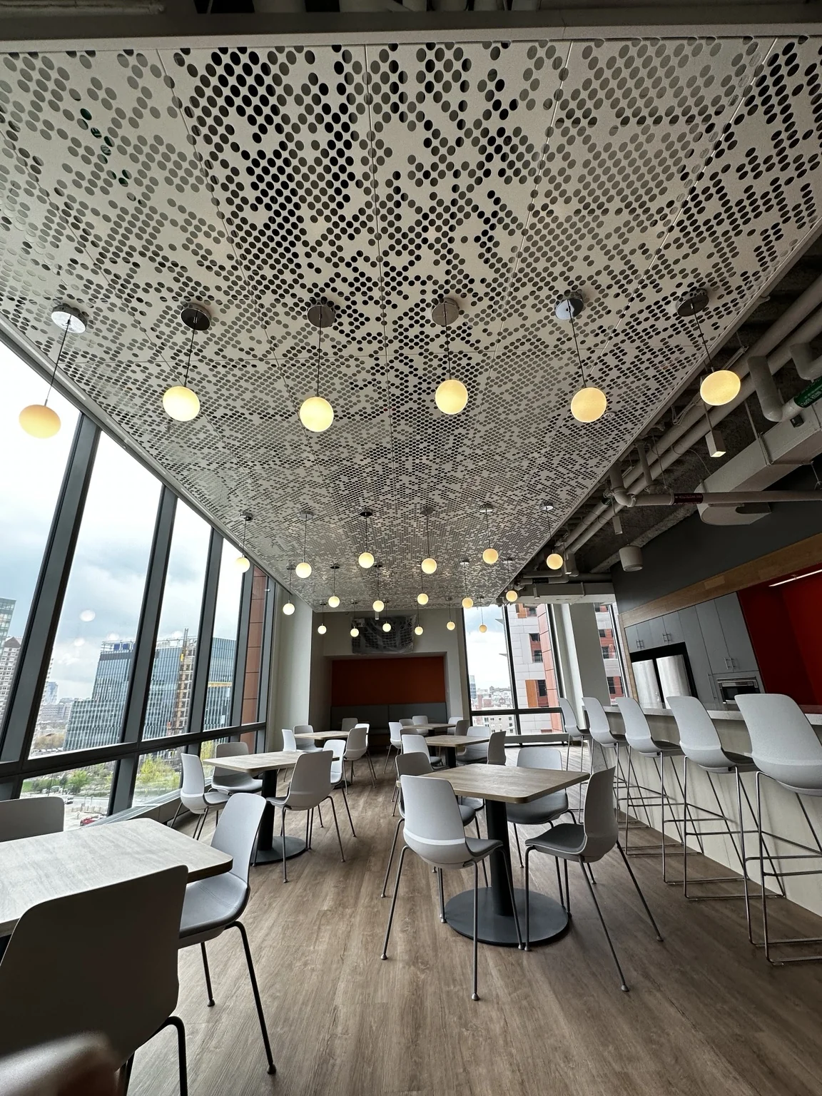 Finished perforated specialty acoustic ceiling with suspended globe lighting