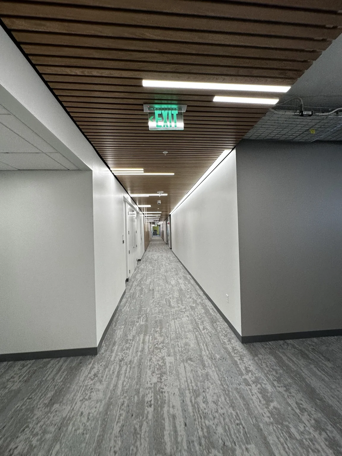 Completed commercial corridor with wood slat ceiling and integrated lighting